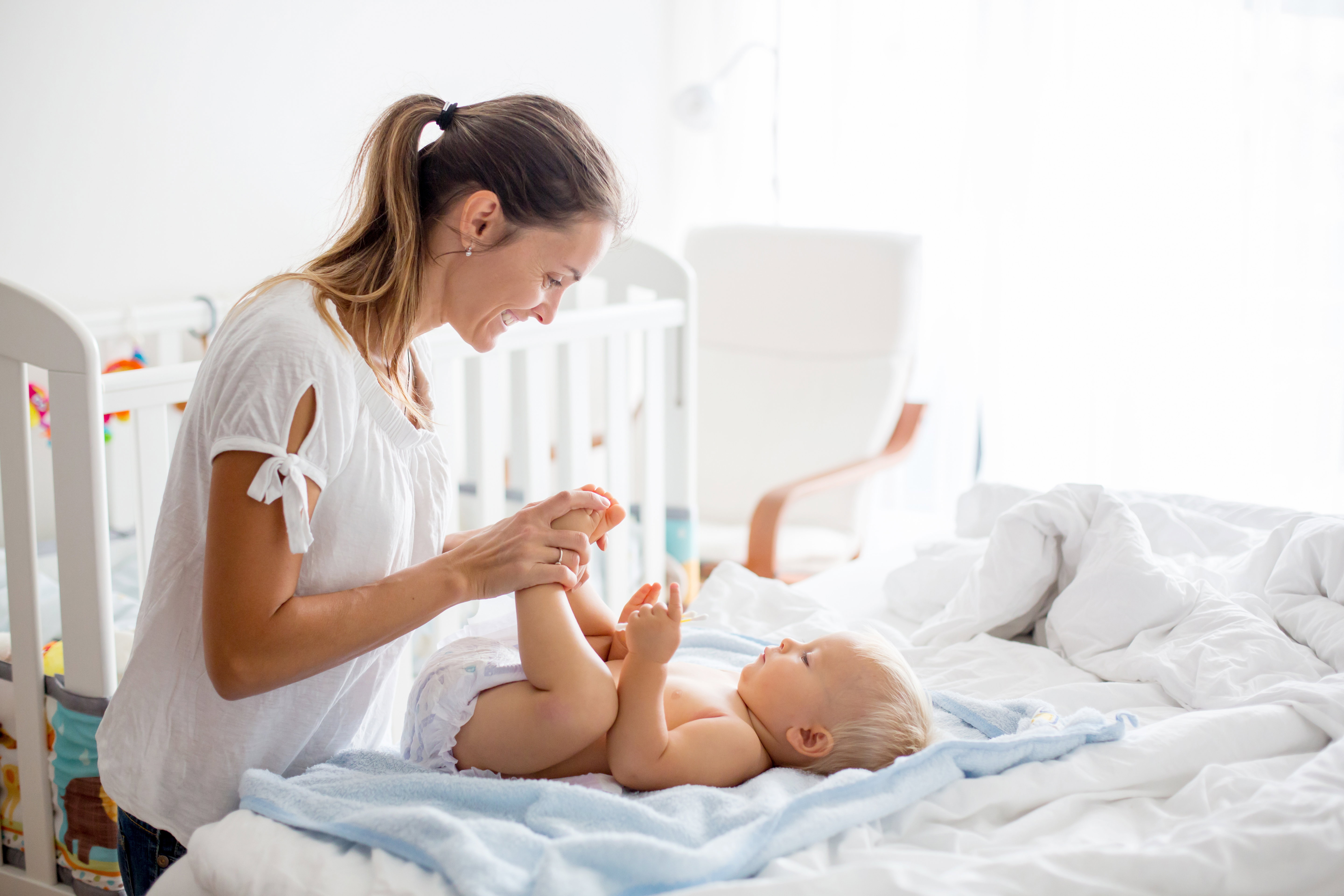 Young mom, changing baby diaper after bath