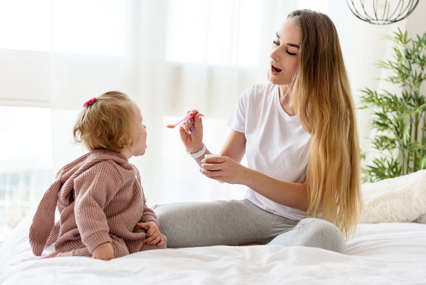 Happy mother feeding baby in bedroom