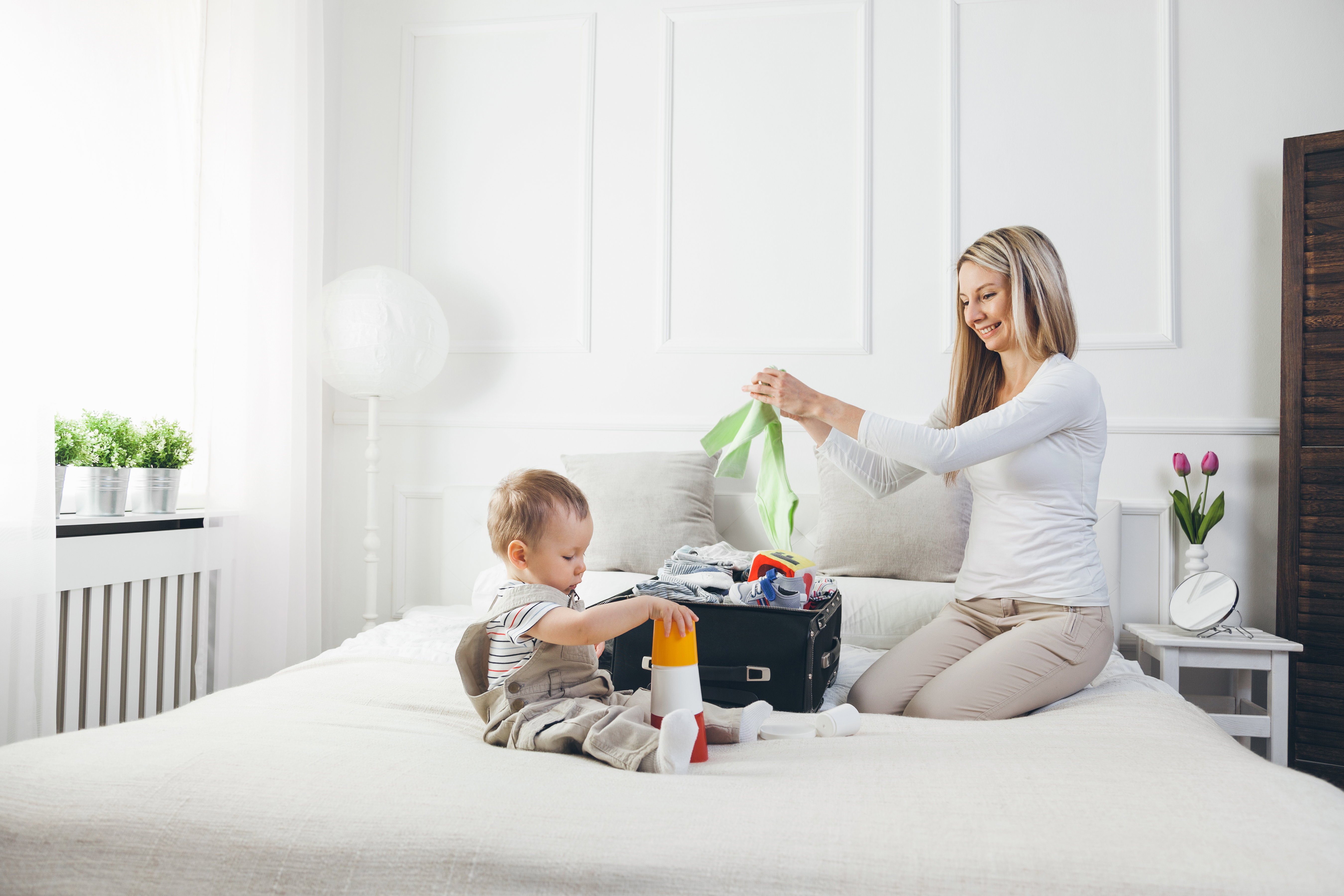 Travelling with kids. Happy mother with her child packing clothes for holiday