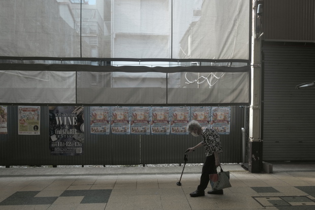 Starsza kobieta przechodzi obok zamkniętego centrum handlowego w Fukuoka w Japoni
