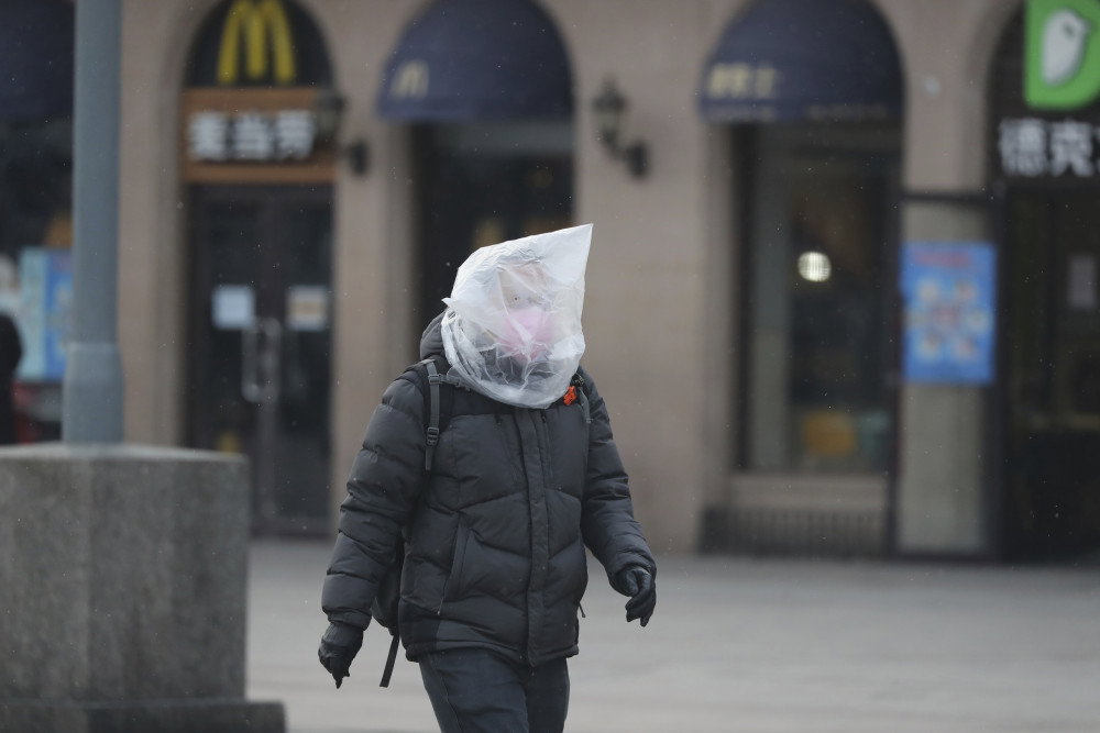 Mężczyzna w masce owiniętej plastikową torbą idzie na stację kolejową w Pekinie 5 lutego 2020 r. fot. Yomiuri Shimbun/Associated Press/East News
