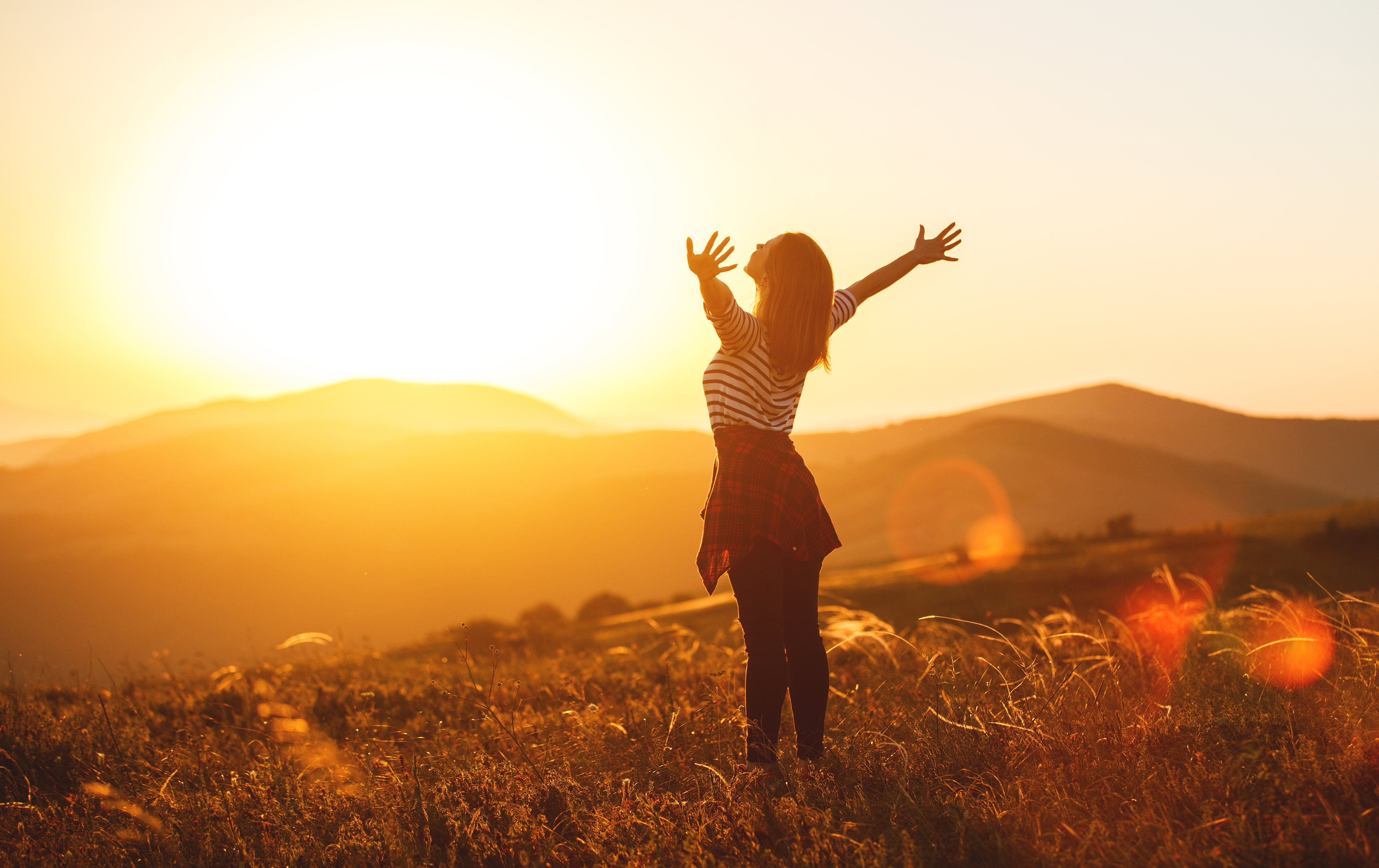 Happy woman jumping and enjoying life  at sunset in mountains