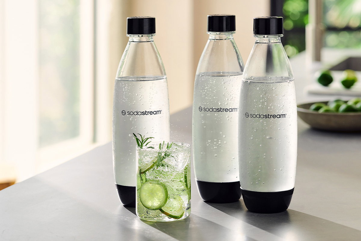 3 butelki SodaStream stojące na blacie w kuchni z wodą gazowaną z dodatkami - tytułowa.