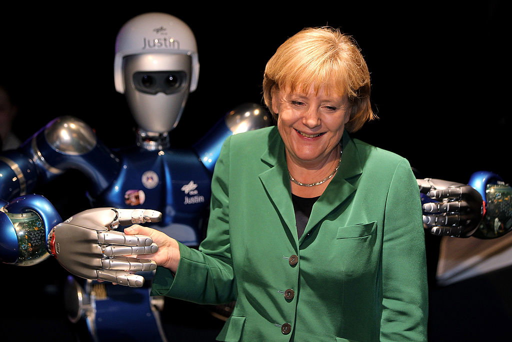 Ówczesna kanclerz Niemiec Angela Merkel pozuje z „Justinem”, robotem w pawilonie podróży kosmicznych na ILA Berlin Air Show 2010