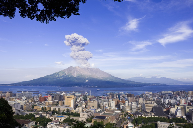 Wulkan Sakurajima unoszący kłęby dymu nad miastem Kagoshima, Japonia.