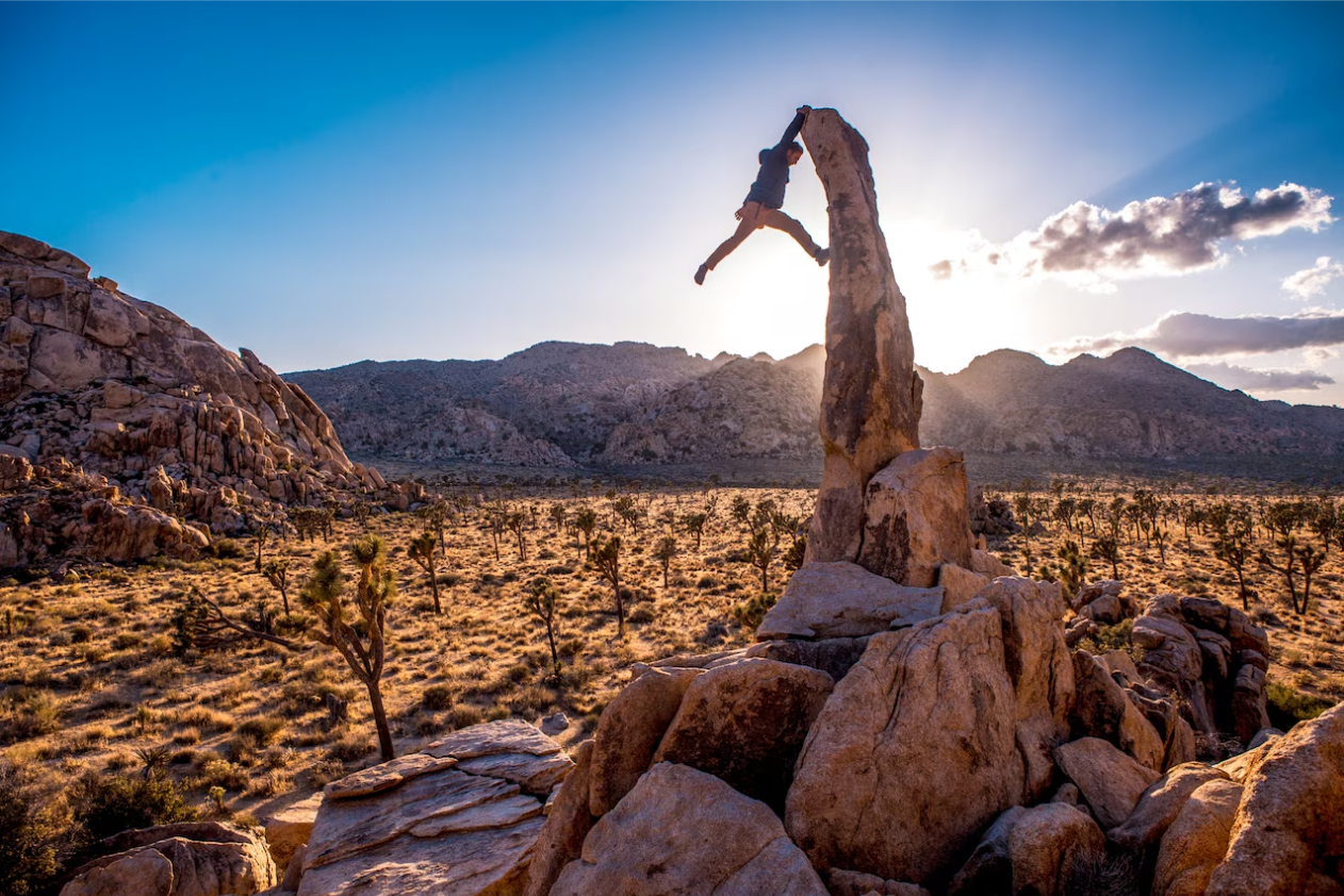 Mężczyzna wspina się na iglicę w Joshua Tree National Park — wspinaczka to pełnowymiarowy trening całego ciała.