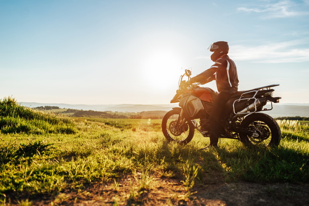 person with helmet on a enduro motorcycle at sunset