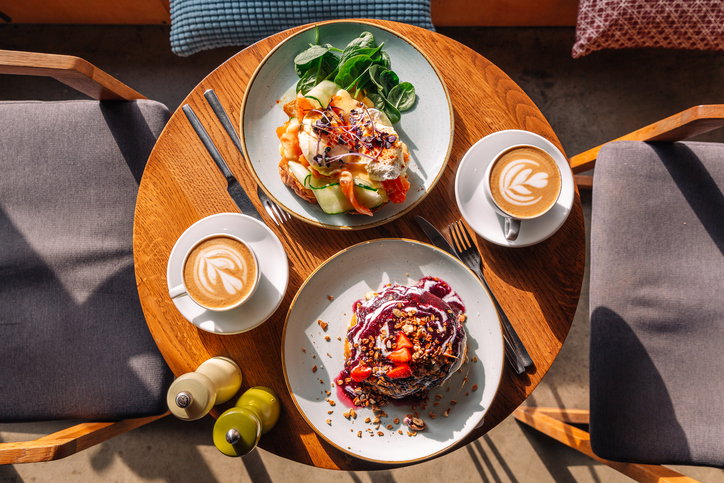 Brunch with sweet pancakes and Eggs Benedict with salmon served in restaurant