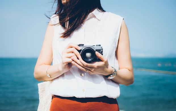 Girl taking photos with vintage film camera in the beach on a sunny day