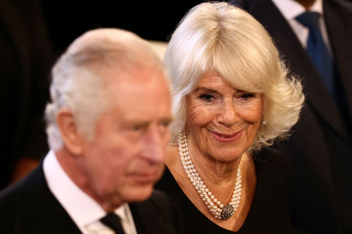 zamyślony król Karol III i uśmiechnięta Camilla