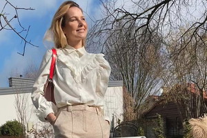 Paulina Sykut w białej letniej bluzce z falbankami i bufkami i beżowych spodniach