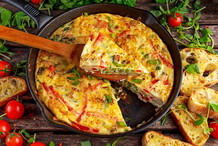 Frittata to popularne danie włoskiej kuchni. Jest to masa jajeczna, którą zapieka się na patelni z serem, szynką oraz warzywami.