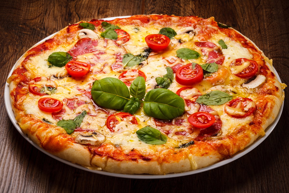 pizza-na-talerzu-lezaca-na-drewnianym-blacie
