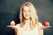 Kobieta wybiera między muffinką a jabłkiem