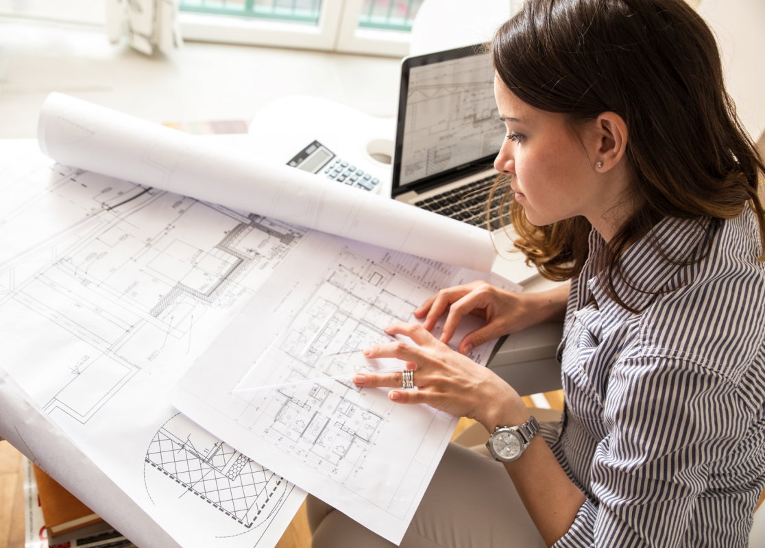 Kobieta pochyla się nad projektem architektonicznym