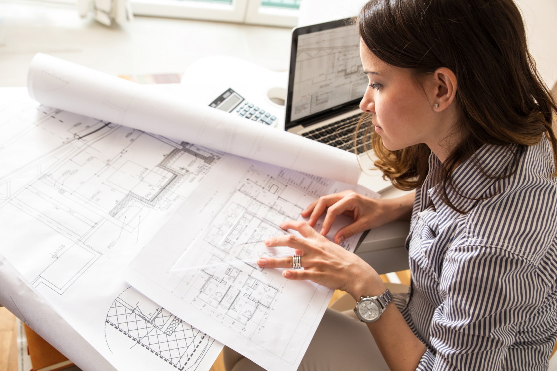 Kobieta pochyla się nad projektem architektonicznym