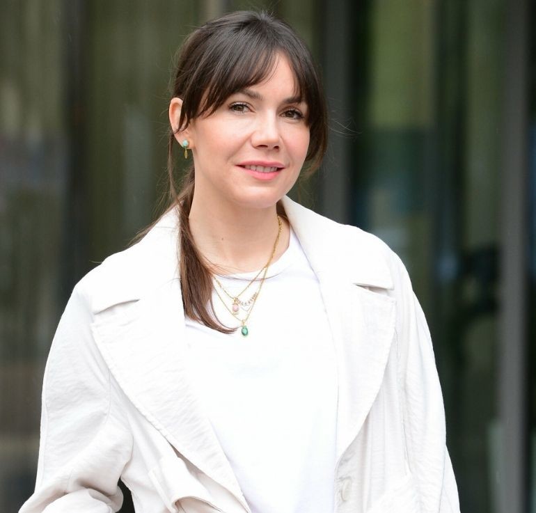 Olga Bołądź w białej bluzce i jasnym płaszczu