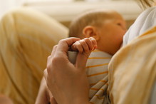 Newborn baby boy sucking milk from mothers breast. Portrait of mom and breastfeeding baby.