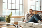 Woman relax in living room, coffee and peace on sofa, content at home with lifestyle and happiness. Female in apartment, happy woman and coffee cup, positive energy and mindset with wellness