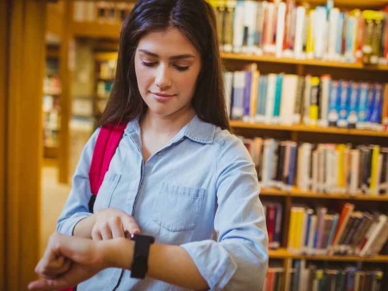 kobieta ze smartwatchem w bibliotece