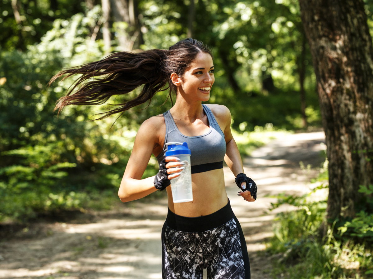 Young woman  jogging outdoor on dirt road at the park .Green environment.