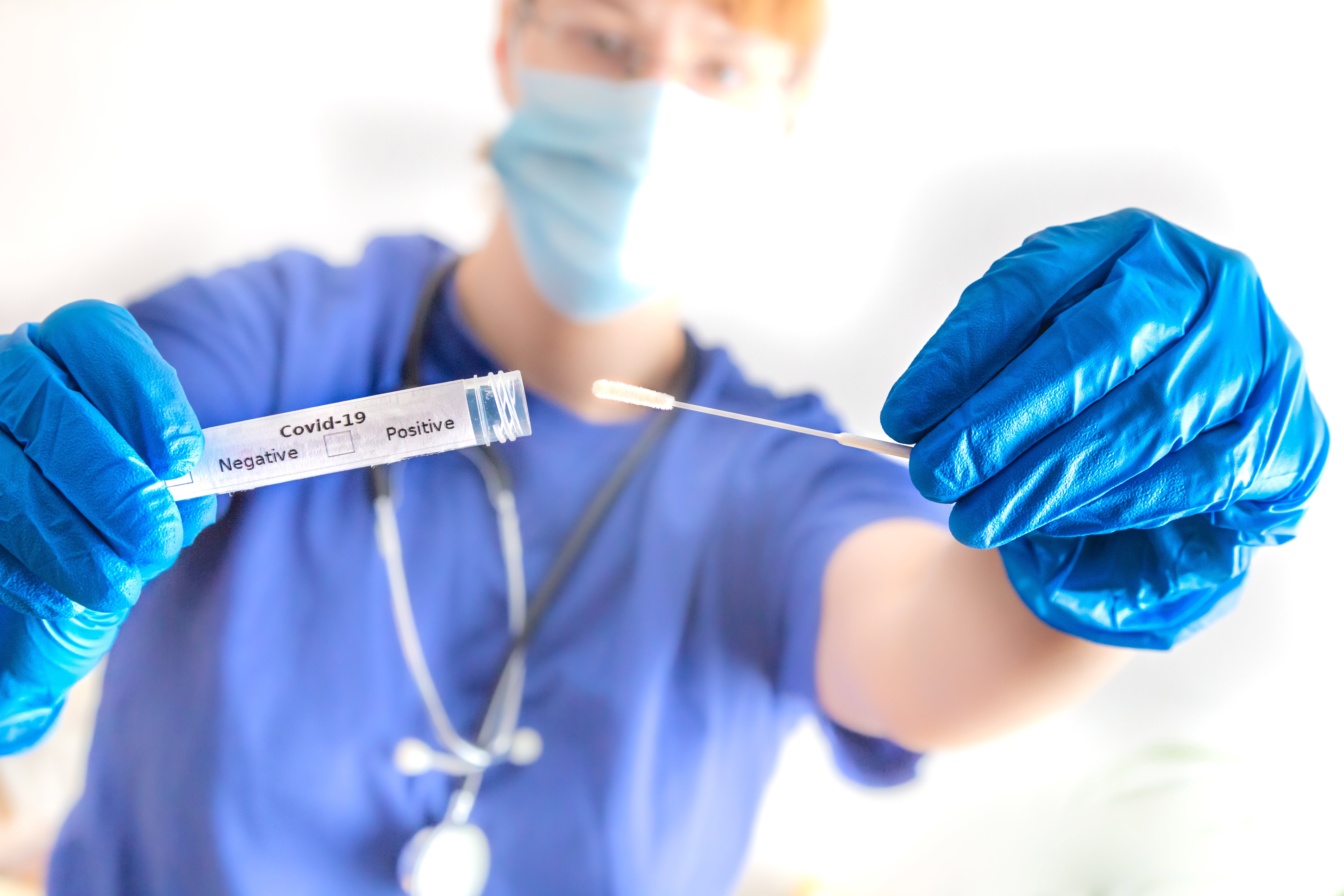 eine Ärztin hält ein Abstrichröhrchen mit Coronavirus in der Hand