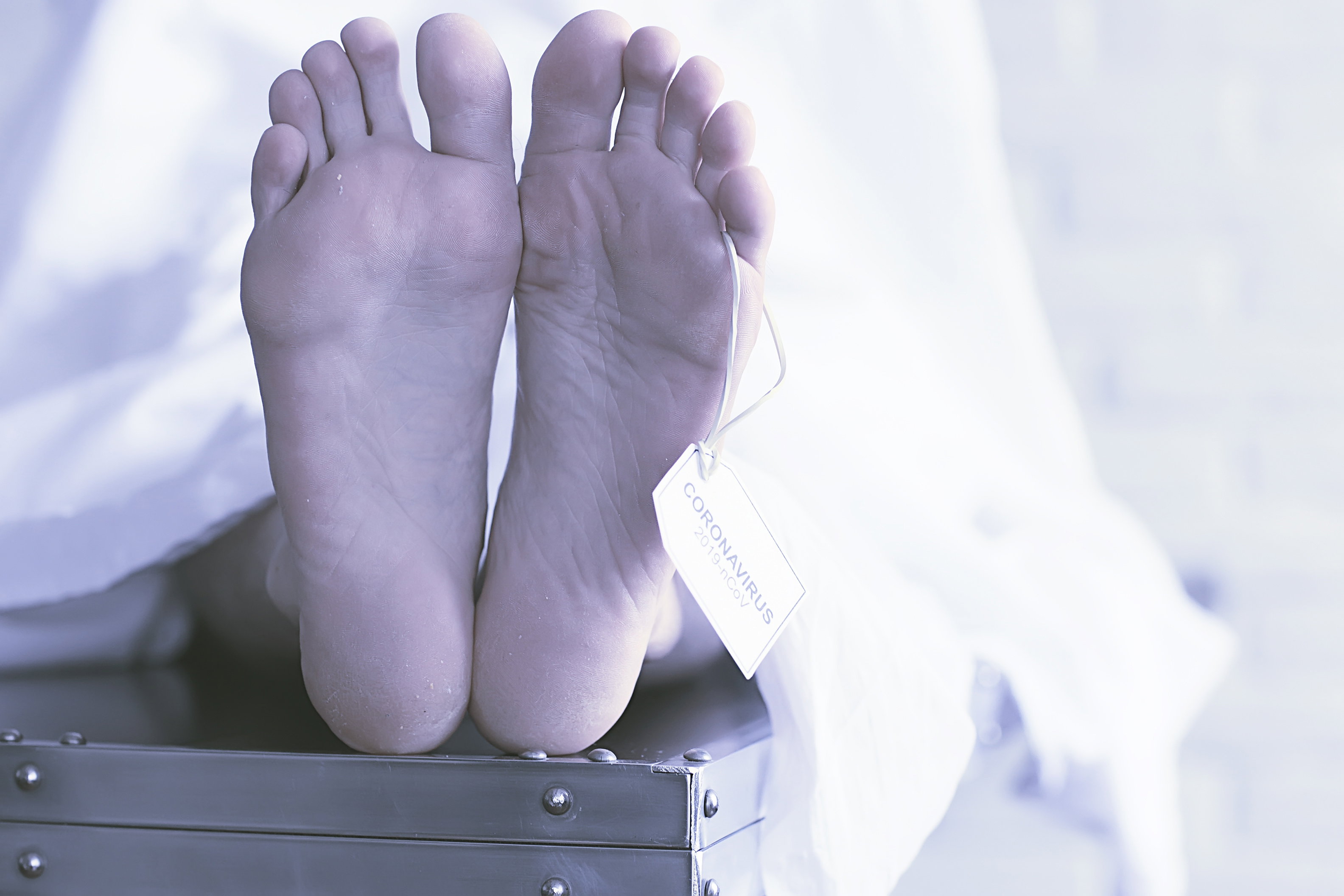 concept imitation morgue, coronavirus victim killed by 2019-ncov, legs of a corpse on a table, man died