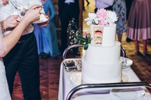 bride and groom cutting delicious wedding cake at reception in restaurant. luxury wedding couple tasting stylish white cake with peony flowers at wedding celebration