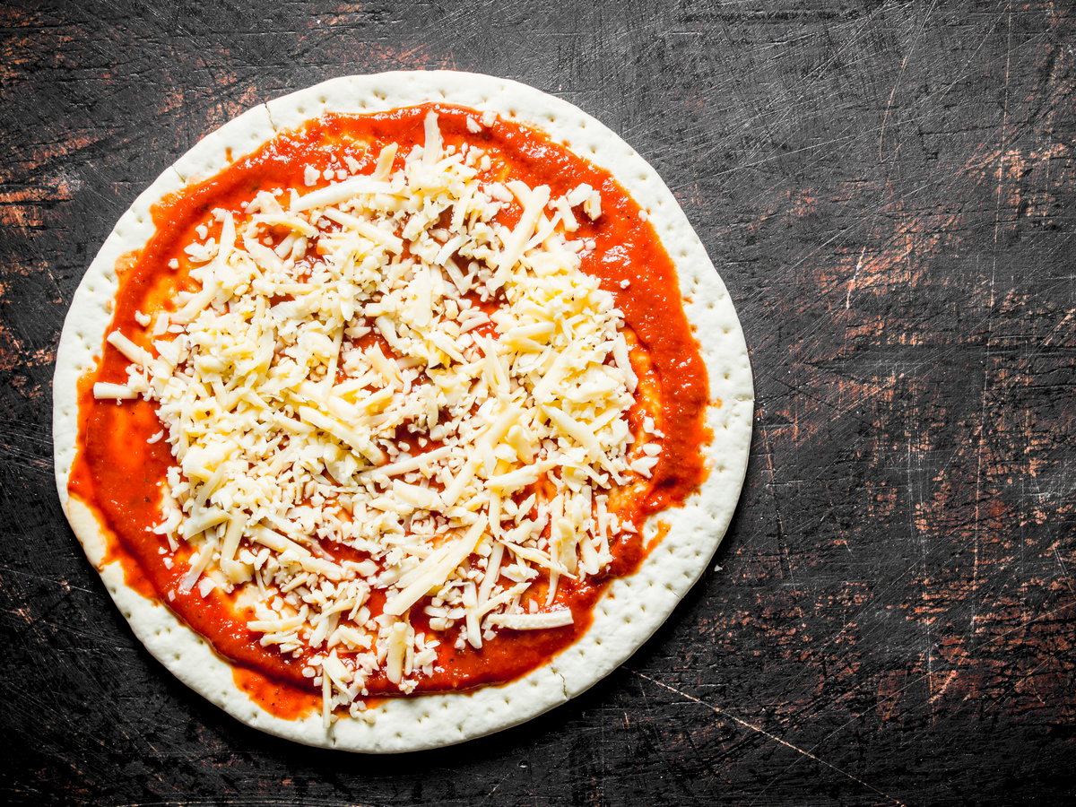 Preparation pizza. Rolled out round dough with tomato paste and cheese.