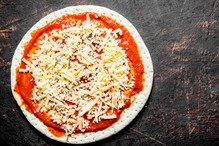 Preparation pizza. Rolled out round dough with tomato paste and cheese.