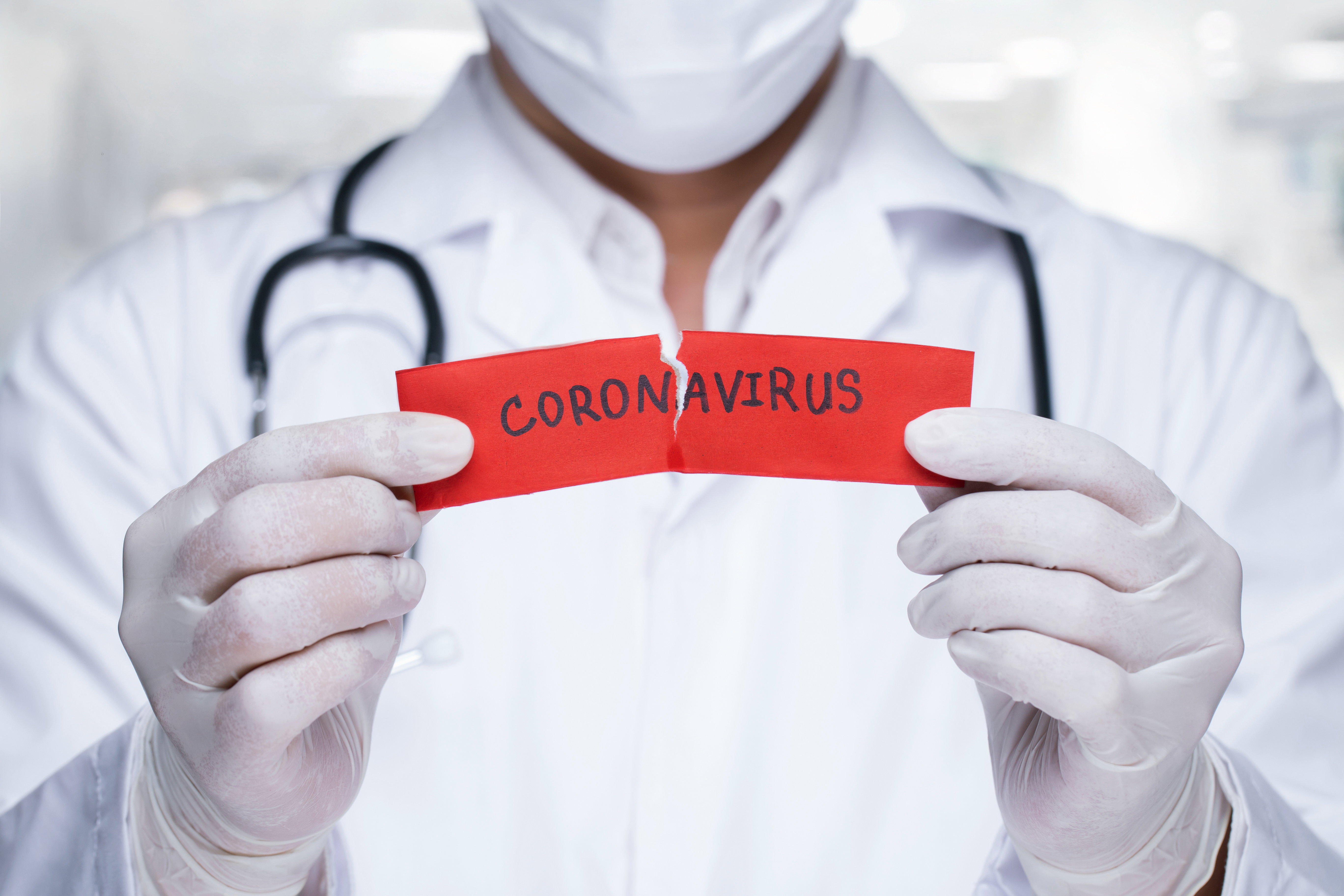 Concept of coronavirus quarantine. MERS-Cov.Novel coronavirus (2019-nCoV).Doctor with a stethoscope Tear the red paper with the word coronavirus.