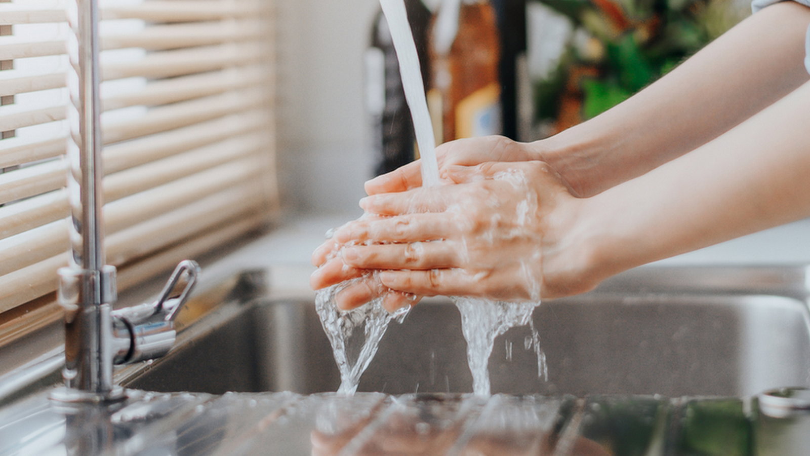 Woman washing hands in sink before cooking in kitchen