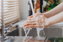 Woman washing hands in sink before cooking in kitchen