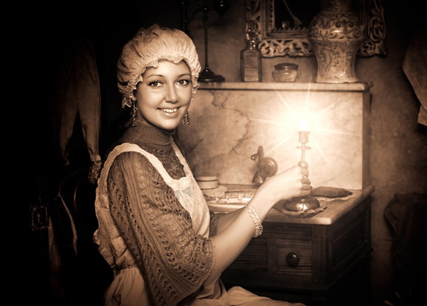 Retro portrait of beautiful woman in old cap with candlestick