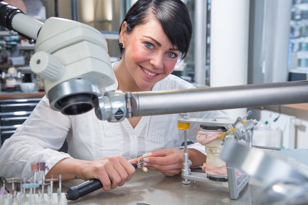Zahntechnikerin in einem Dentallabor mit Zahnersatz.