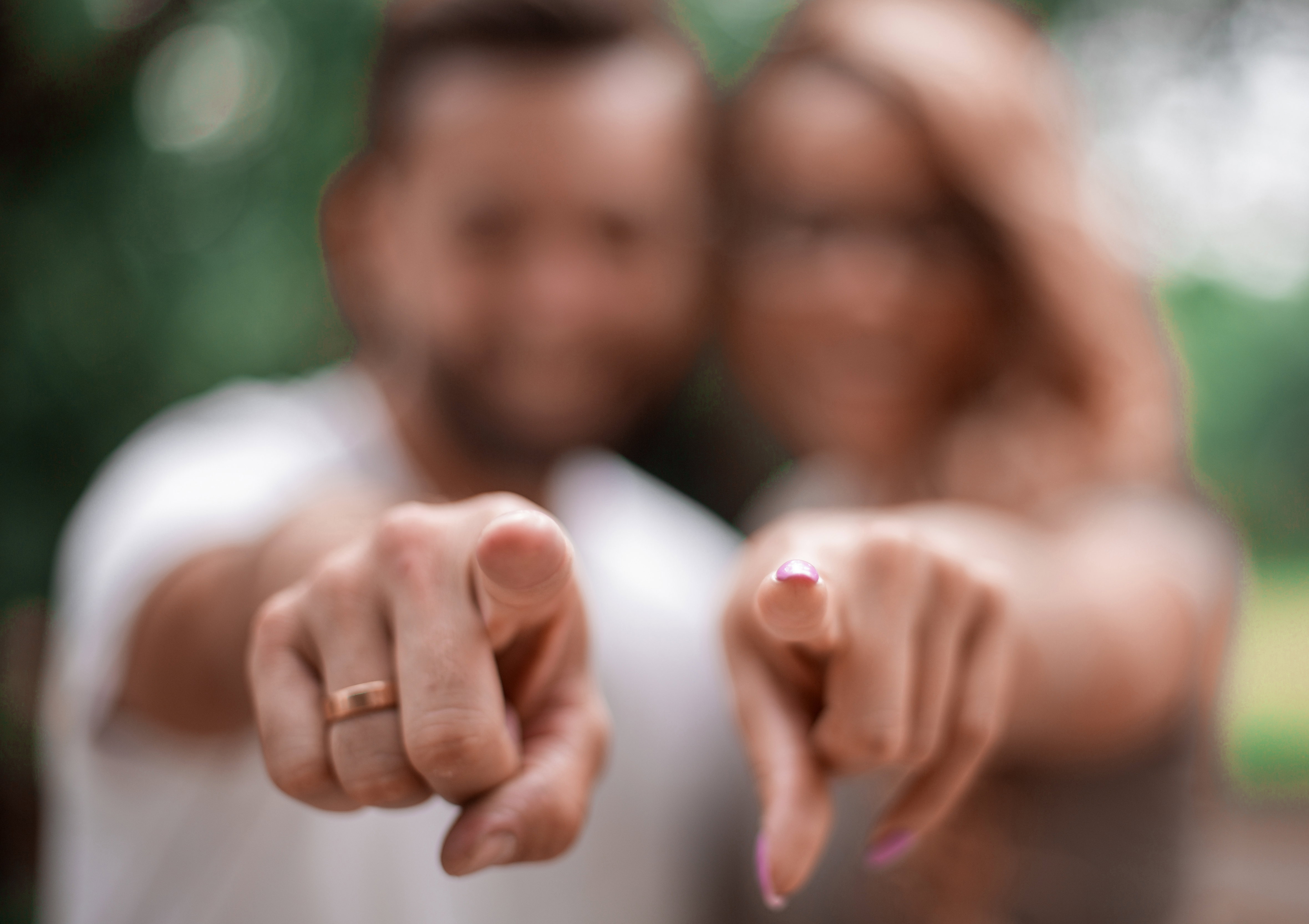 happy married couple standing in the Park and pointing at you.