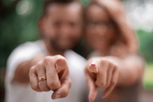 happy married couple standing in the Park and pointing at you.