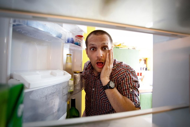 Shocked men looking in his empty fridge