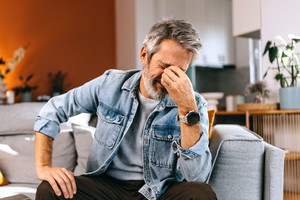 Stressed Senior Man Sitting on Sofa at Home