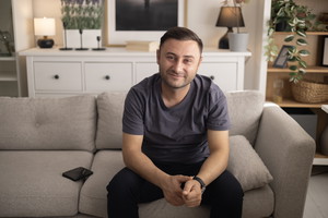 Adult man enjoying free time, sitting on a comfortable sofa in his modern living room, looking at camera