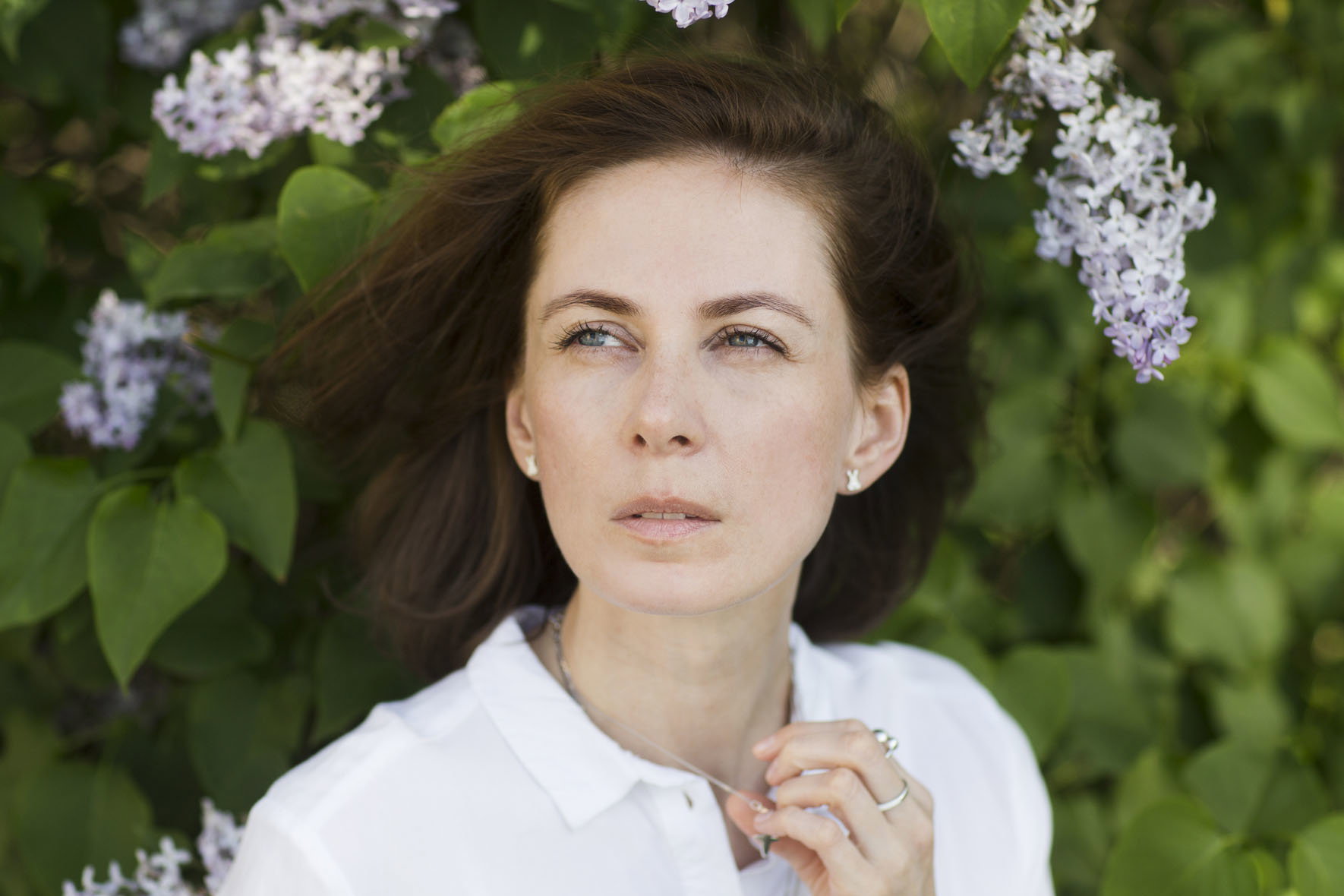 sad middle aged woman near the flower lilac bush relaxed outdoors. copy space. concept without stress. mental health. Slow life. Enjoying the little things. spends time in nature in summer