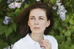 sad middle aged woman near the flower lilac bush relaxed outdoors. copy space. concept without stress. mental health. Slow life. Enjoying the little things. spends time in nature in summer