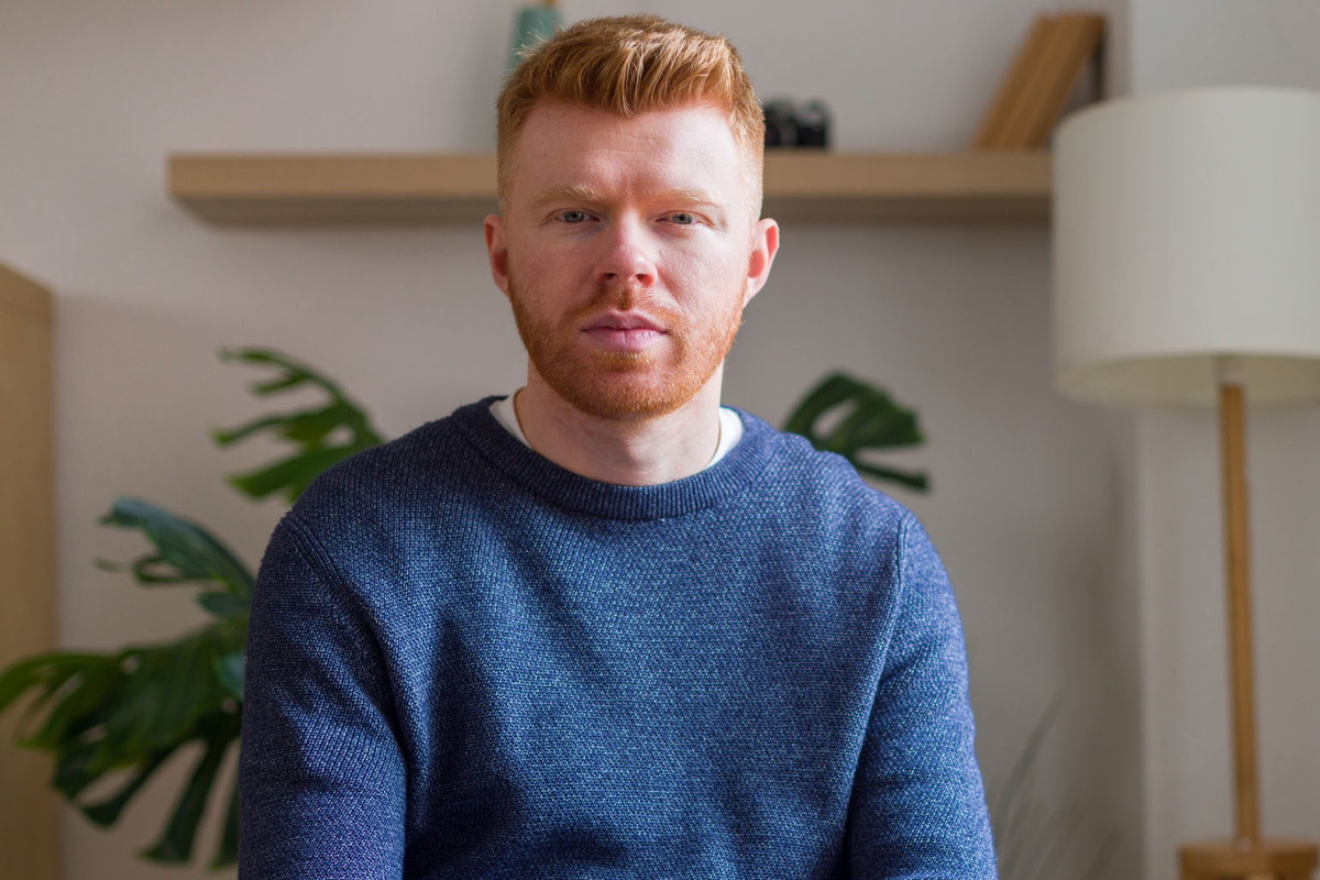 Serious young adult man sitting looking at camera