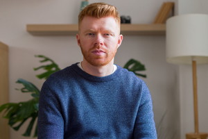 Serious young adult man sitting looking at camera
