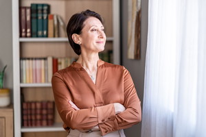 Mature woman looking out window thinking about future