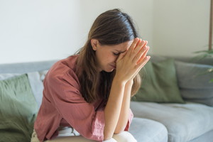 Sad young woman on sofa in living room