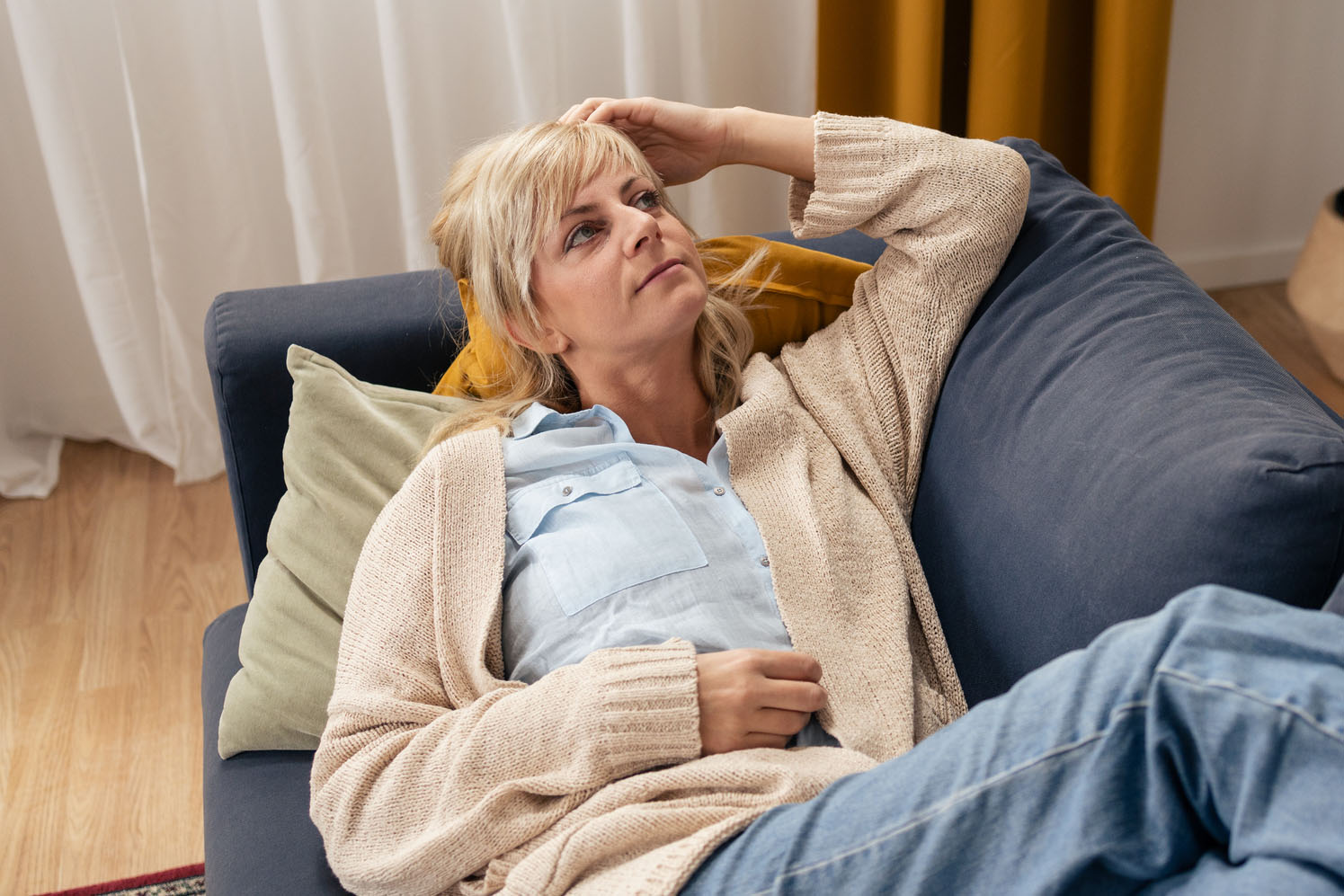 Mature woman relaxing on sofa thinking at home