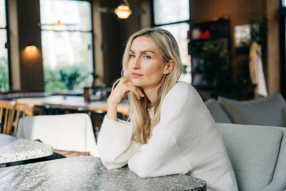 Beautiful pensive blonde woman with long hair sitting in a cafe.