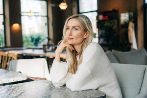 Beautiful pensive blonde woman with long hair sitting in a cafe.