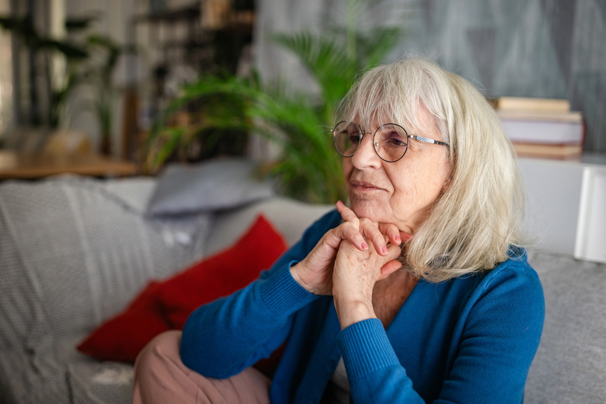 Thoughtful senior woman resting on sofa at home